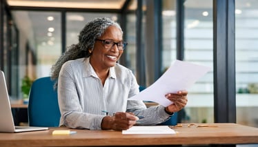 Firefly a happy mature black woman on office desk looking at a document; blurred office background 5